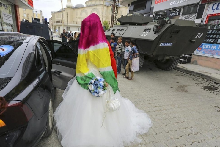 A bride, whose face is covered by a scarf with yellow-red-green Kurdish national colors, gets in a wedding car, near armored Turkish police vehicles in Yuksekova in the Kurdish province of Hakkari, Turkey, Sep. 6, 2015. (Photo: Reuters)