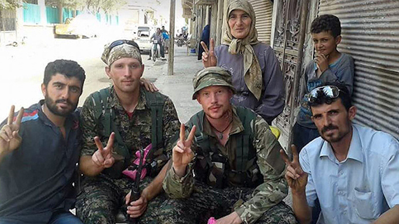 Joseph A. R. (second from right) is, in this undated picture, seen making a victory sign along with civilians and another fighter presumably in Syrian Kurdistan (Rojava).