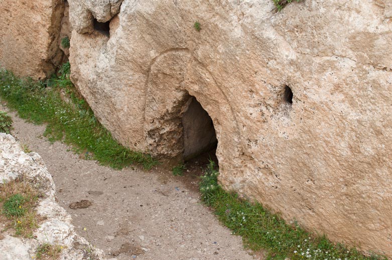 There is a large, decorated cave in the design of a nave with niches on one end and a raised platform on the other end. 