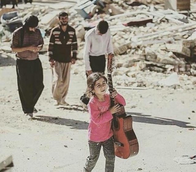A young Kurdish girl saving her guitar after the earthquake destroyed her city. (Photo: Social Media)