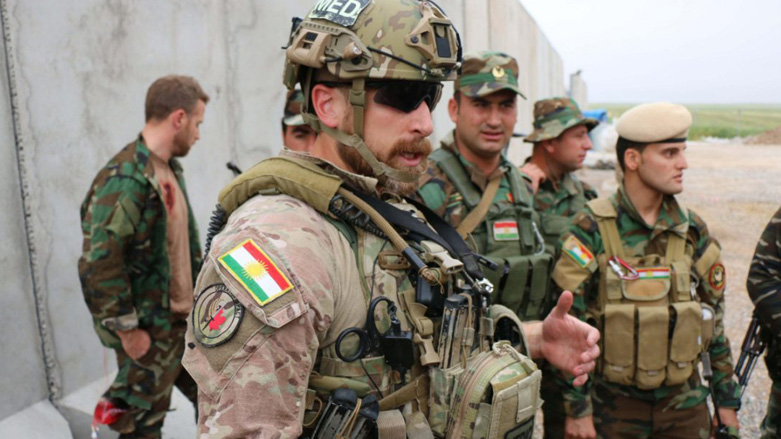 A Canadian special forces soldier, foreground, working in the Kurdistan Region with local Peshmerga soldiers, wears the Kurdish flag on his uniform. (Photo: Toronto Star/Bruce Campion-Smith)