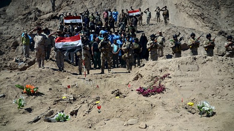 Iraqi soldiers salute the graves where the soldiers were found. (Photo: Reuters)