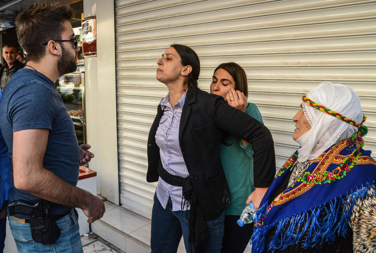 MP Feleknas Uca tries to prevent an armed Turkish police officer from arresting a woman during demonstrations against the government crackdown on opposition politicians in the Kurdish city of Diyarbakir, Turkey, October 2016. (Photo: DHA)