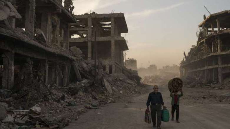 In this Nov. 15, 2017, file photo, Haider (L) and Abdullah carry belongings they collected from their damaged house to wash before returning to live in the Old City of Mosul, Iraq. (Photo: Associated Press/Felipe Dana)