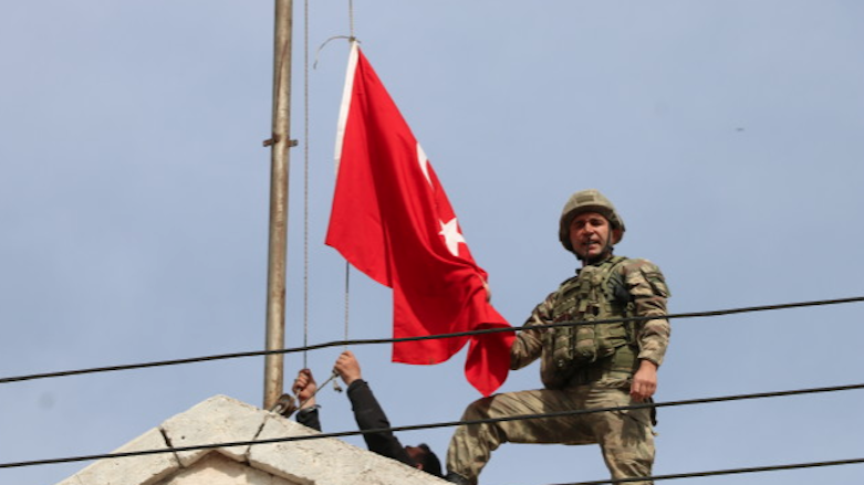 A Turkish soldier raises the Turkish flag over the administrative headquarters of the self-declared canton of Afrin, after invading the town in Syrian Kurdistan, March 18, 2018. (Photo: AA)