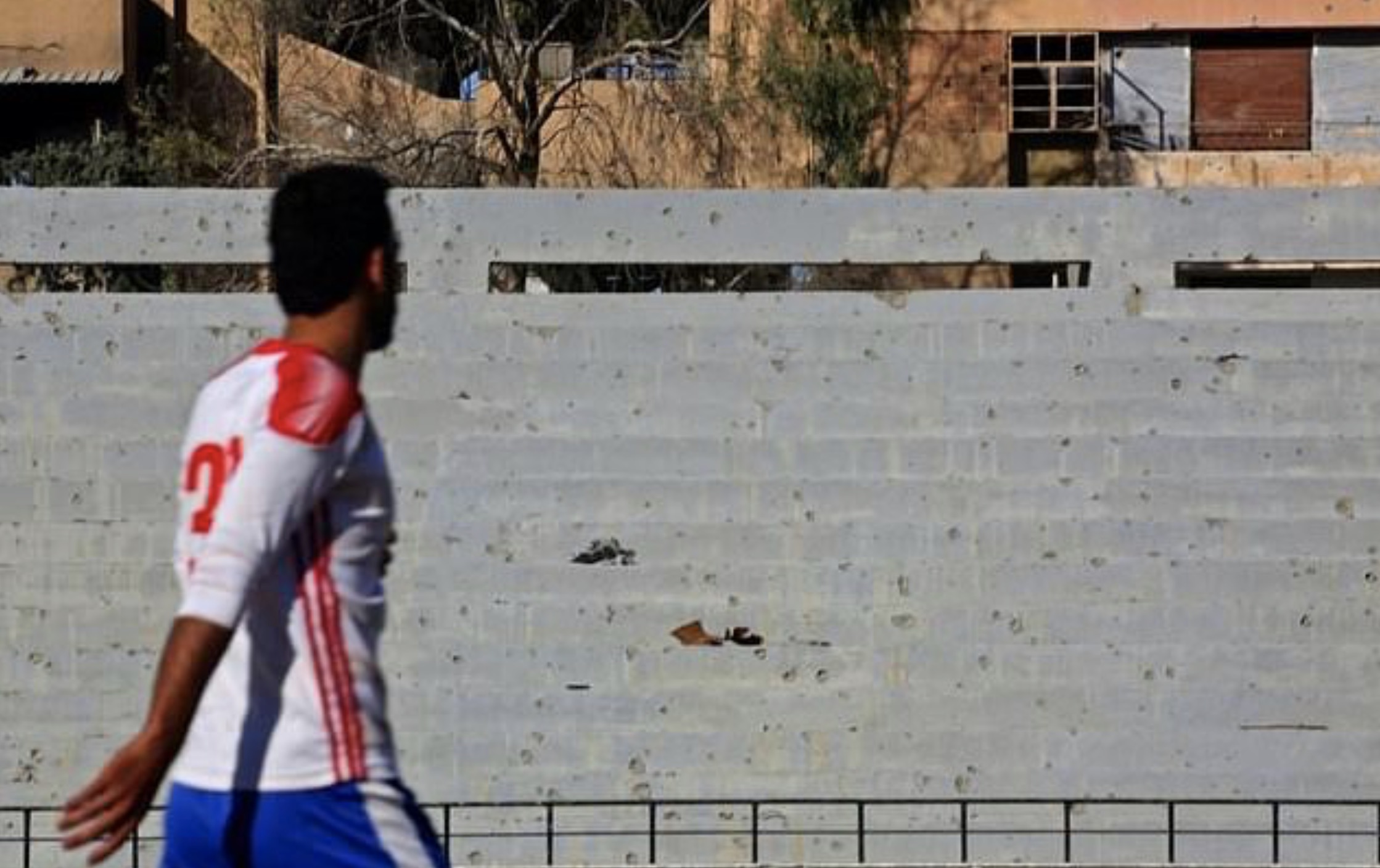 A Syrian player walks past shrapnel riddled stands during a football match on April 16, 2018, between local teams at a stadium in Raqqa that the Islamic State once used as a prison. (Photo: AFP)
