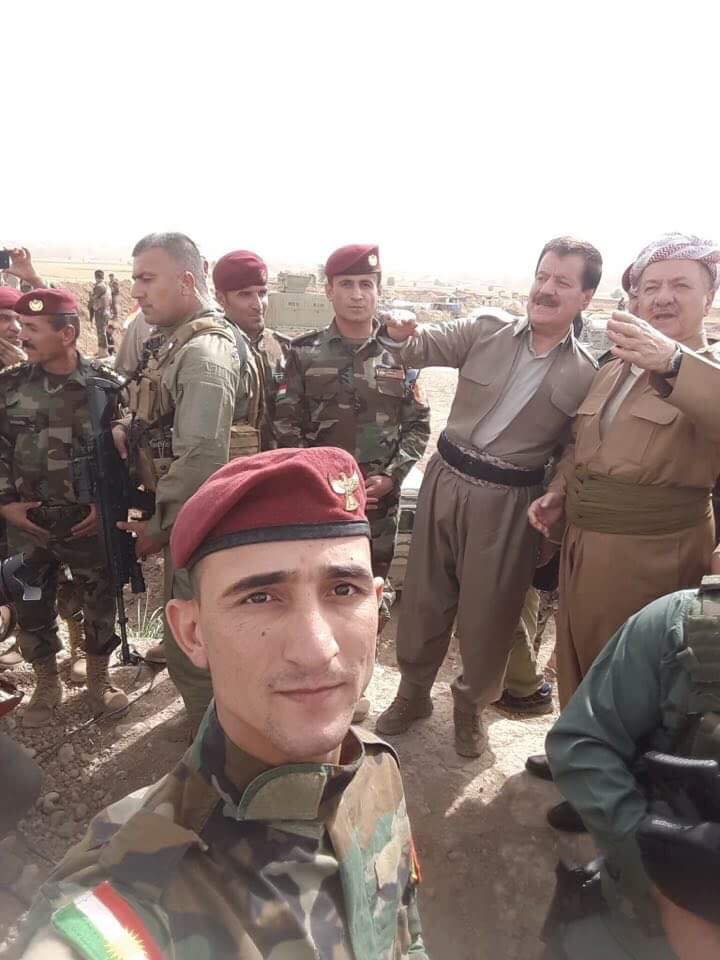 A Peshmerga takes a selfie as KDP President Masoud Barzani (right) and Peshmerga Commander Kemal Kirkuki speak during the Kurdish leader's visit to troops near the town of Perde (Altun Kupri), north of Kirkuk, on June 16, 2018. 