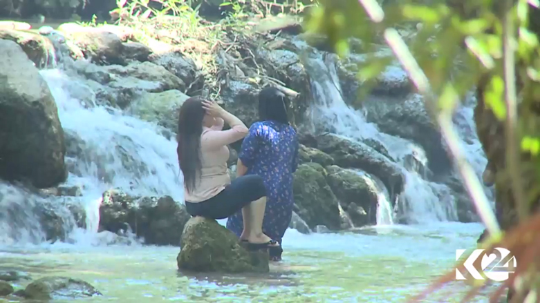Two women cool off at a spring in the Kurdistan Region. 