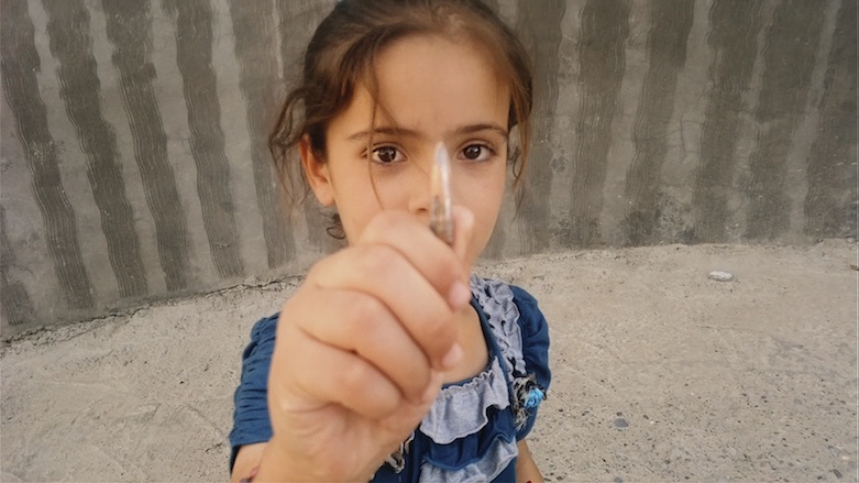 Nori Sharif's daughter, Sarah, holds a bullet casing she found on the ground as the family flees their home in Jalawla due to the Islamic State's emergence. (Photo: Ten Thousand Images)
