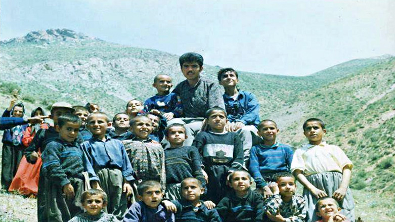 فرزاد کمانگر در میان جمعی از دانش آموزان خود در شهرستان کامیاران، عکس آزشیوی است