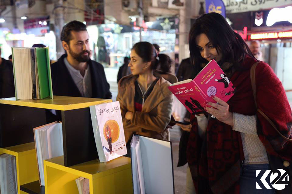 People walking down Salim Street’s sidewalk pause at a bookstore to check out some of the reads available.