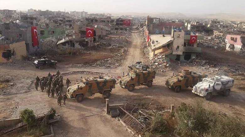 Turkish soldiers and army vehicles seen in front of a destroyed neighborhood where they hung Turkish flags on demolished houses, 2016. (Photo: Social media)