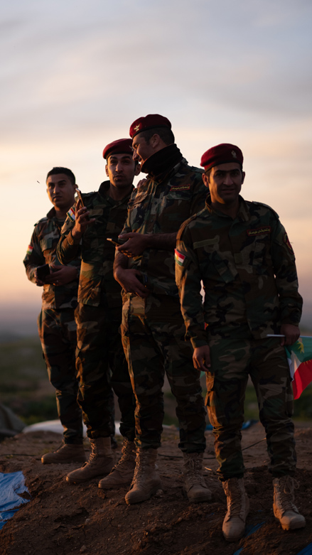 Peshmerga watching the bonfire being lit. (Photo: Levi Clancy/Kurdistan 24)