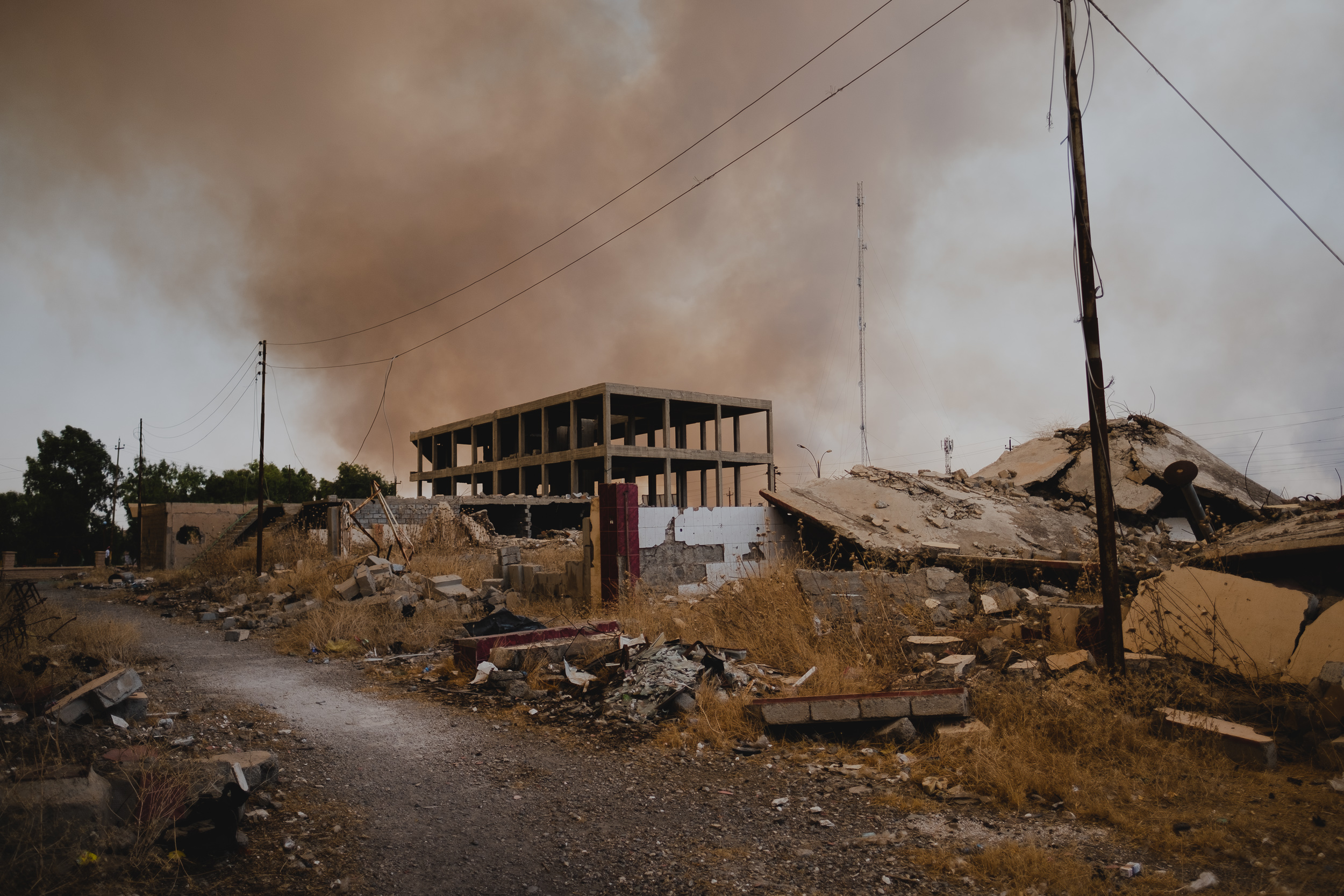Smoke in the background rises over the ruins of coalition airstrikes in the center of Shingal. (Photo: Kurdistan 24/Levi Clancy)