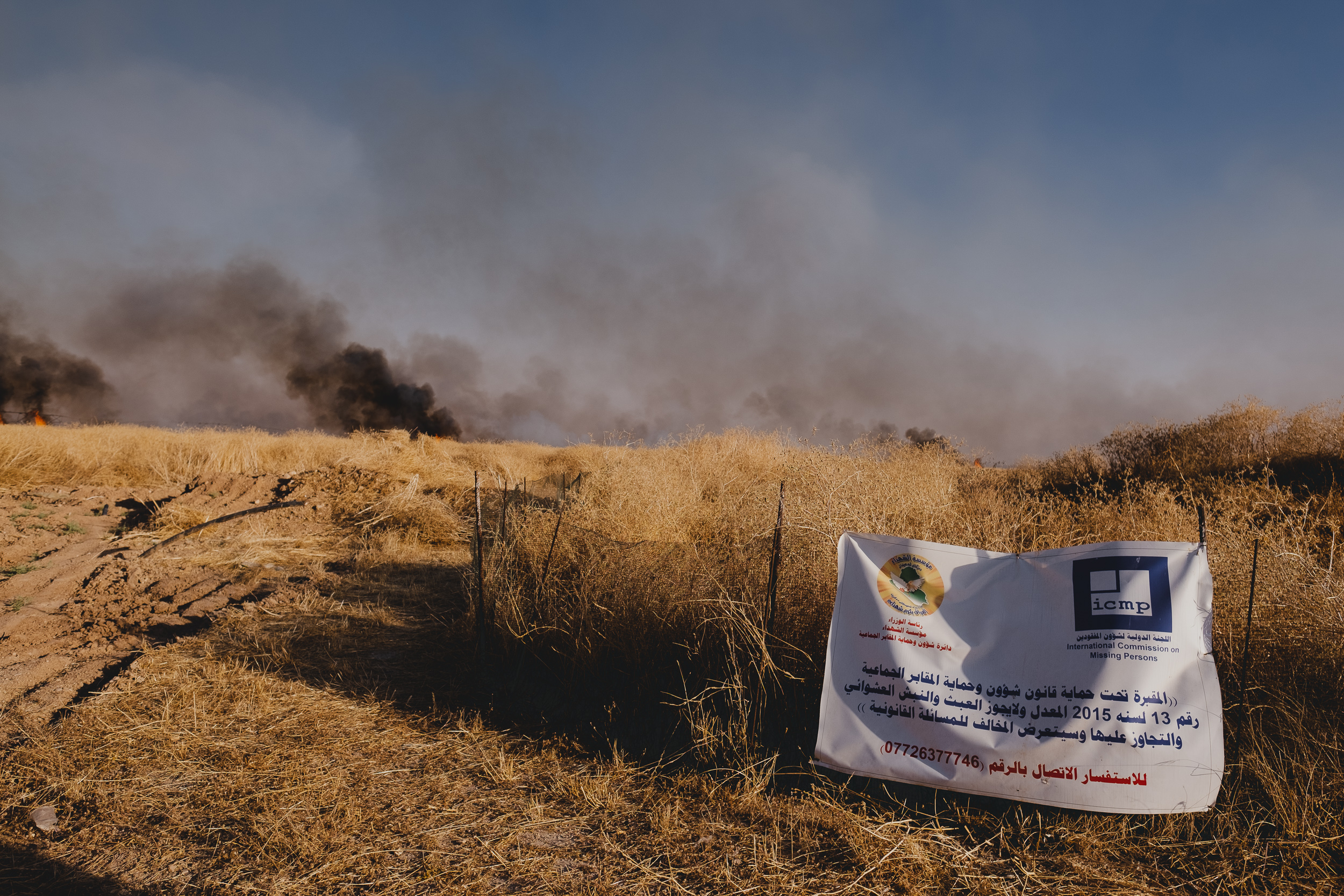This mass grave site marks where 12 men were executed at the Barakat Mahmoud Khero farm, and 28 women and girls and one baby were abducted. The banner announces the mass grave is protected. (Photo: Kurdistan 24/Levi Clancy)