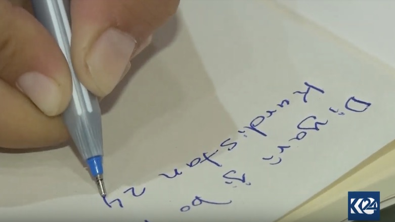 Xelil Muse signs a copy of his book. (Photo: Kurdistan 24)