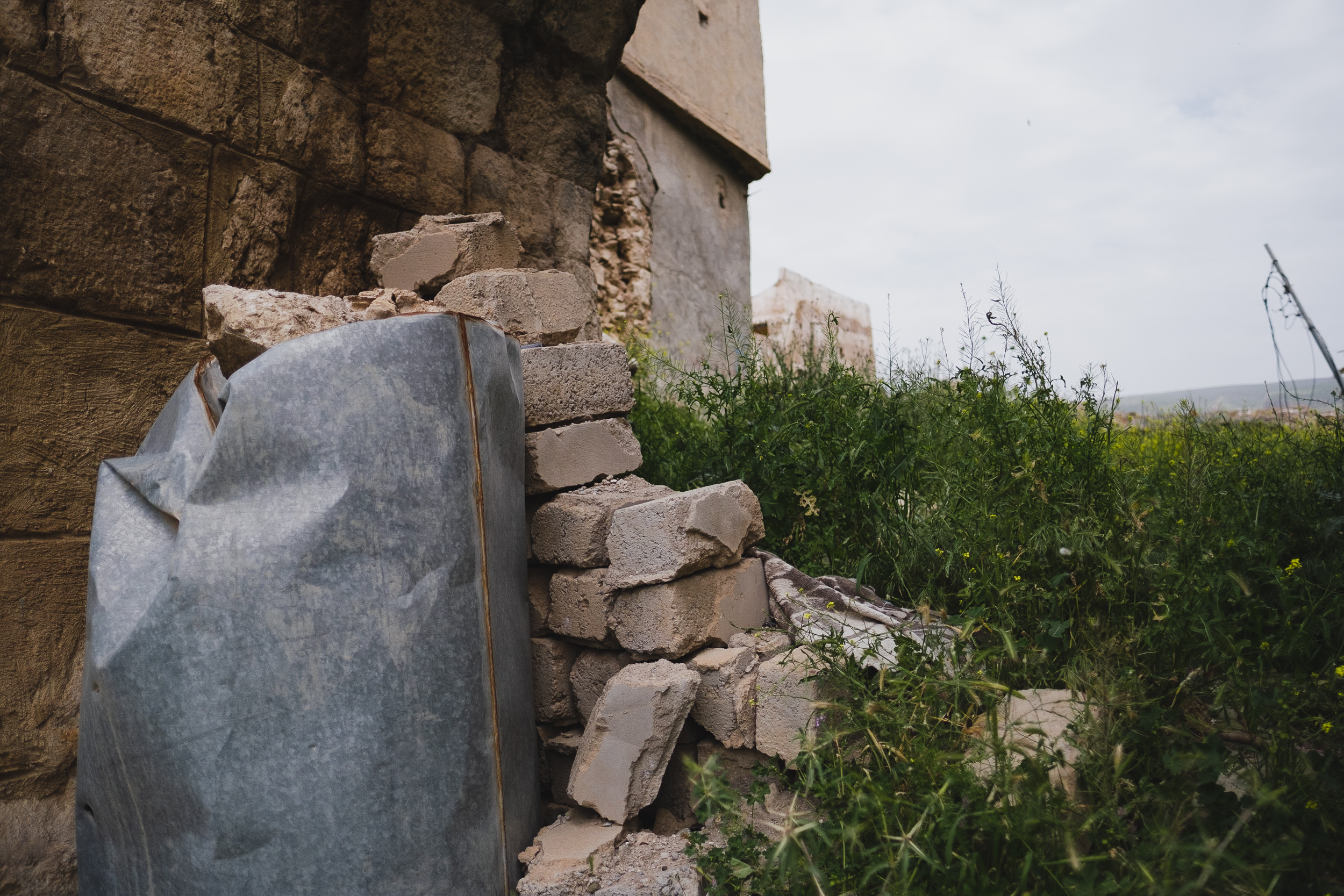 Today, the Roman gate has one of the battle walls that infuse almost every corner and street of Shingal due to war with the Islamic State. These walls are made out of rock-filled water tanks, cinder blocks, and/or sandbags. (Photo: Kurdistan 24/Levi Clancy)