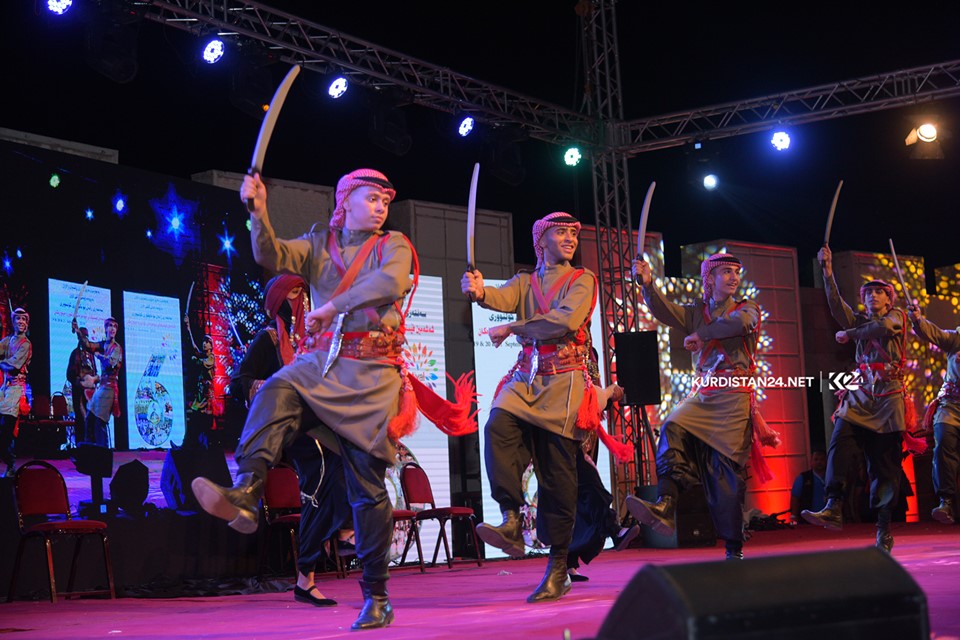 A group of dancers wearing traditional attire performing on stage in the Kurdistan Region city of Rania during a cultural exchange event, Sept. 19, 2019. (Photo: Kurdistan 24/Ismael Shamzini)