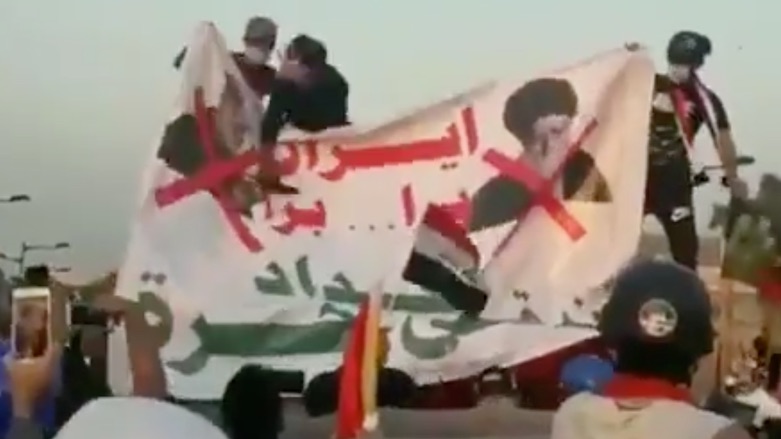 A screen-grab from a video shared on social media shows protesters hitting pictures of Soleimani and Khamenei.