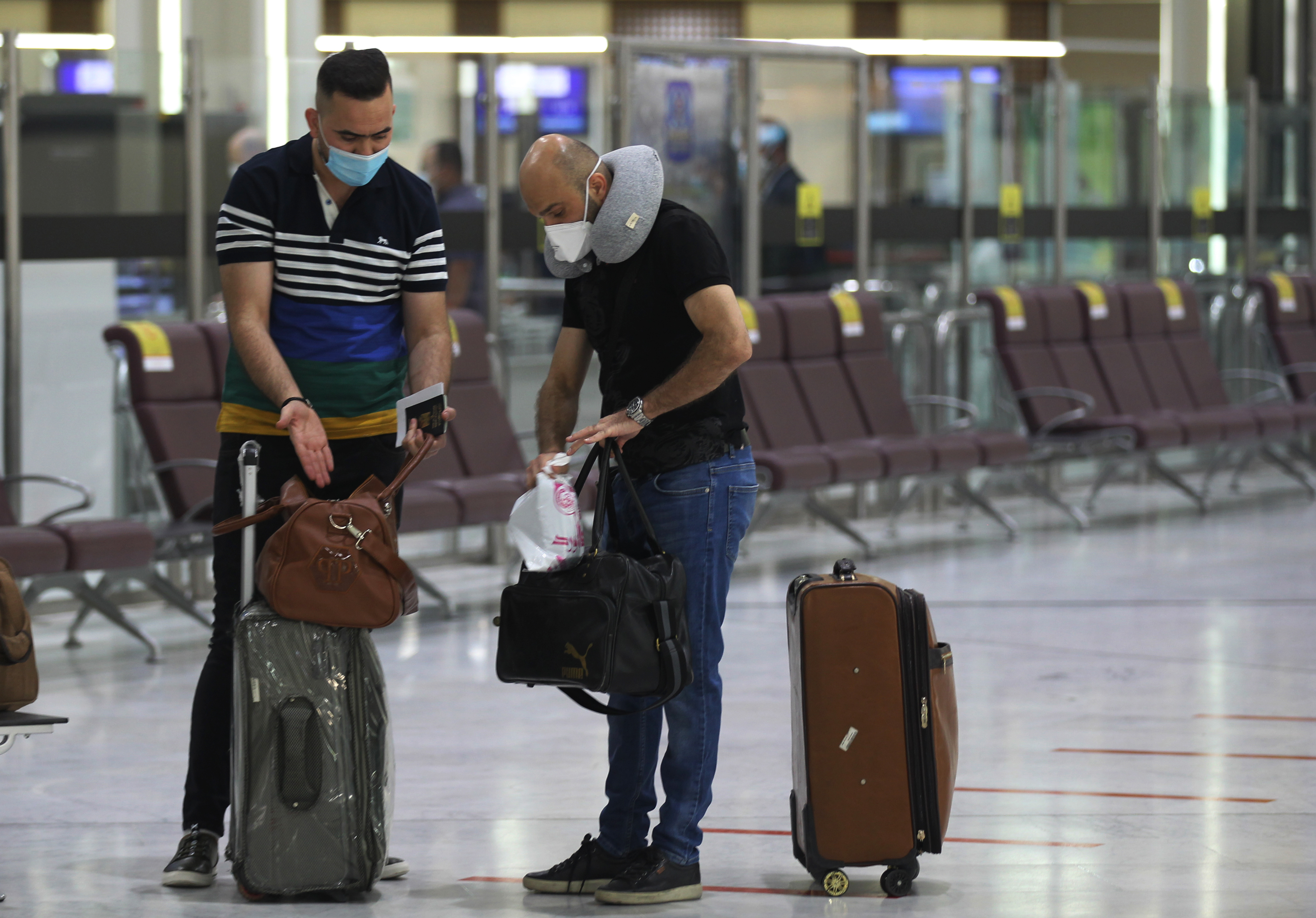 Passengers wearing protective masks wait for flights at the departure hall of Baghdad International Airport, July 23, 2020. (Photo: AFP/Ahmad al-Rubaye)