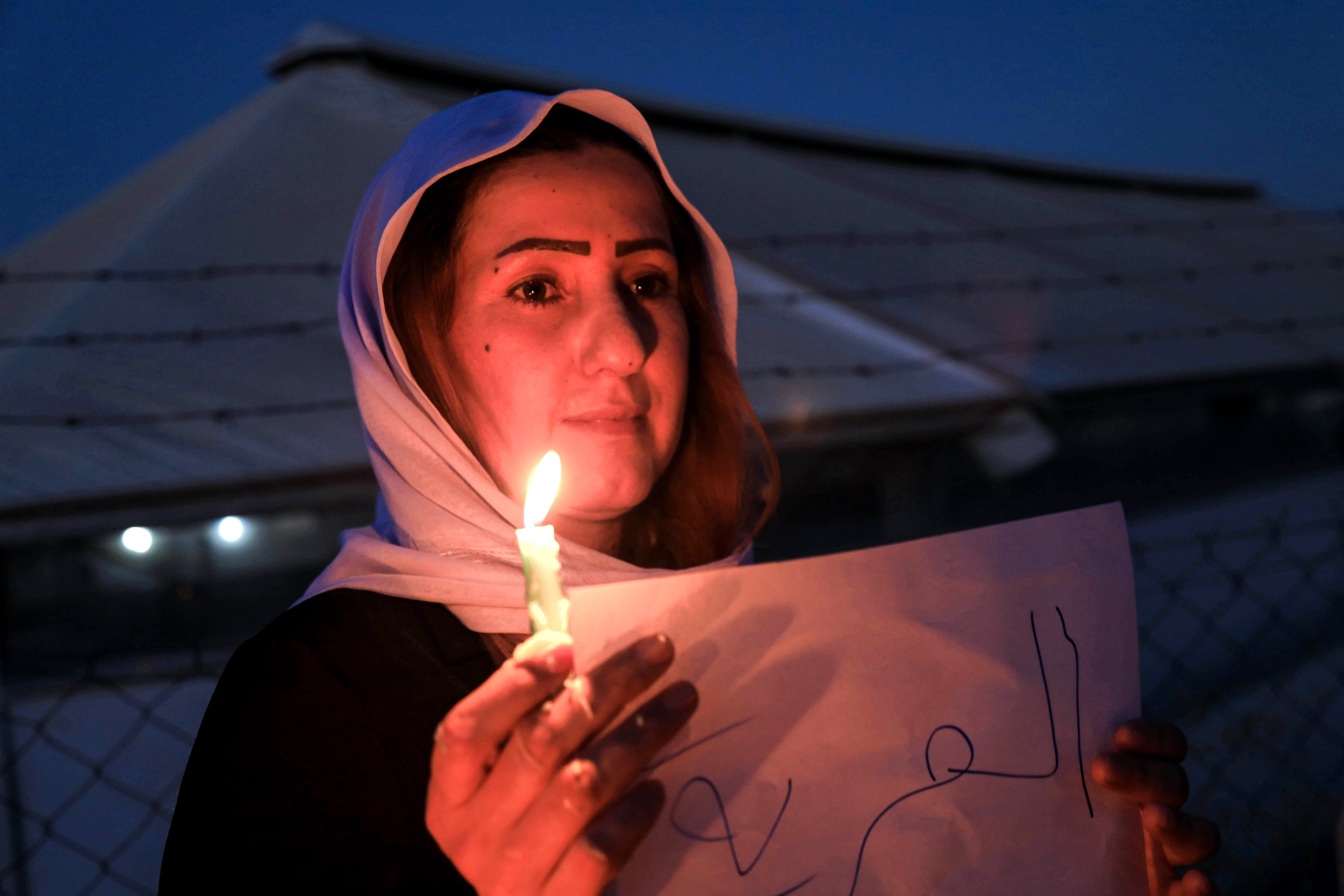A Yezidi (Ezidi) woman holds a candle during a vigil to mark the sixth anniversary of the Yezidi genocide, August 3, 2020.  (Photo: AFP/Safen Hamid)