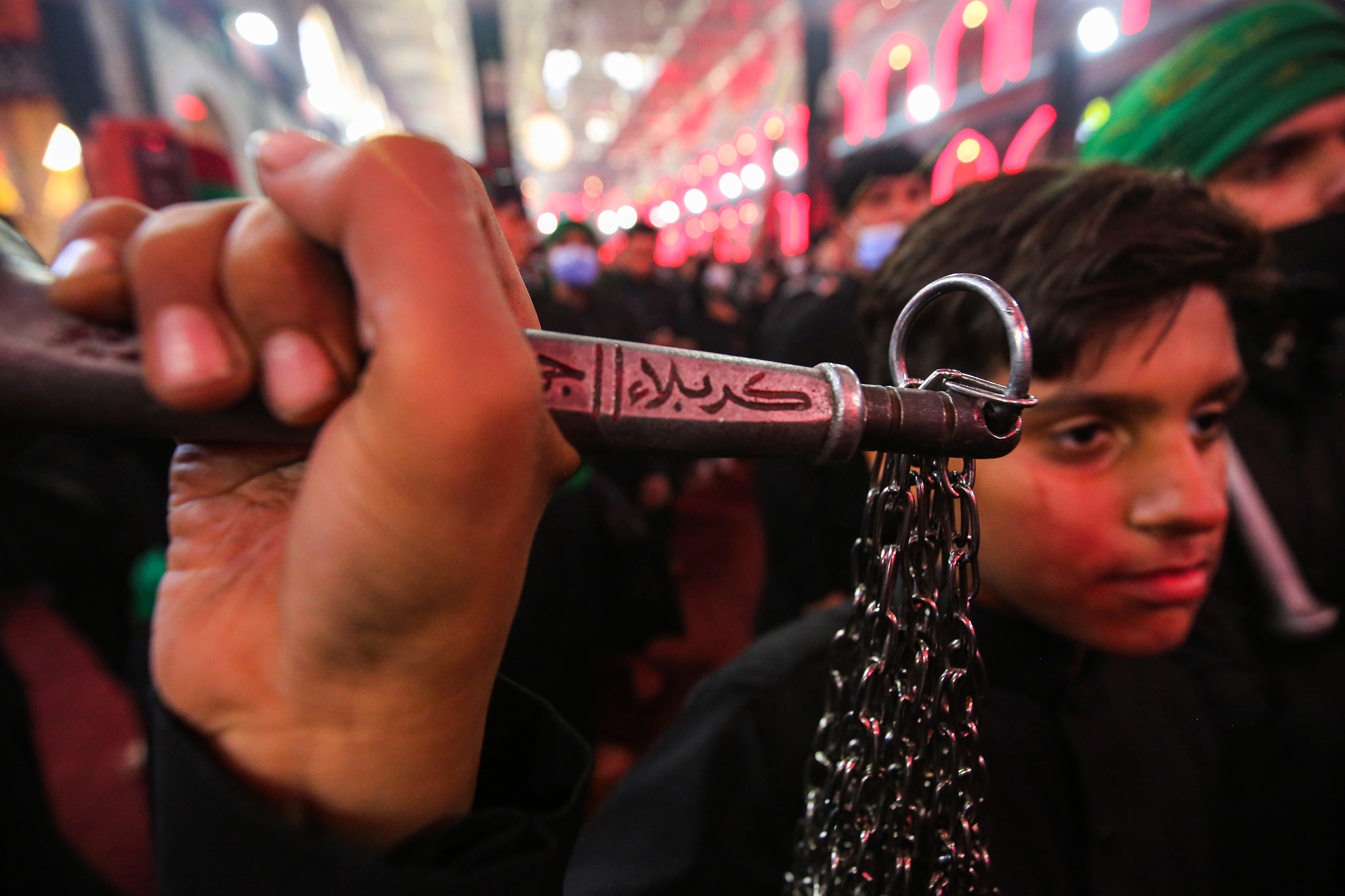 A Shia Muslim worshipper holds a flagellum bearing the name 