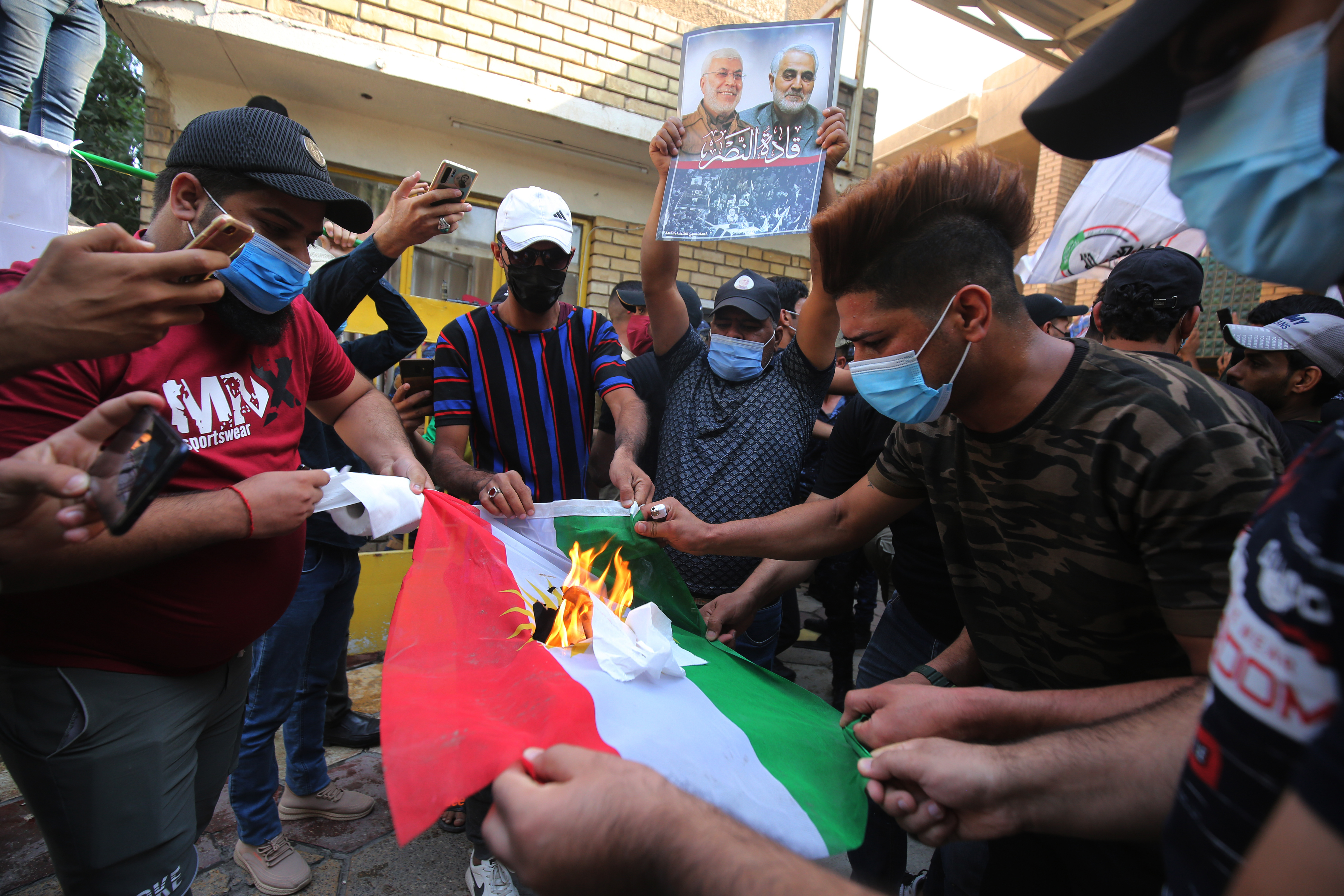 Supporters of Iraq's Popular Mobilization Forces (PMF) militias burn a Kurdistan flag during an attack on a Baghdad office of the Kurdistan Democratic Party, Oct. 17, 2020. (Photo: AFP/Ahmad al-Rubaye)