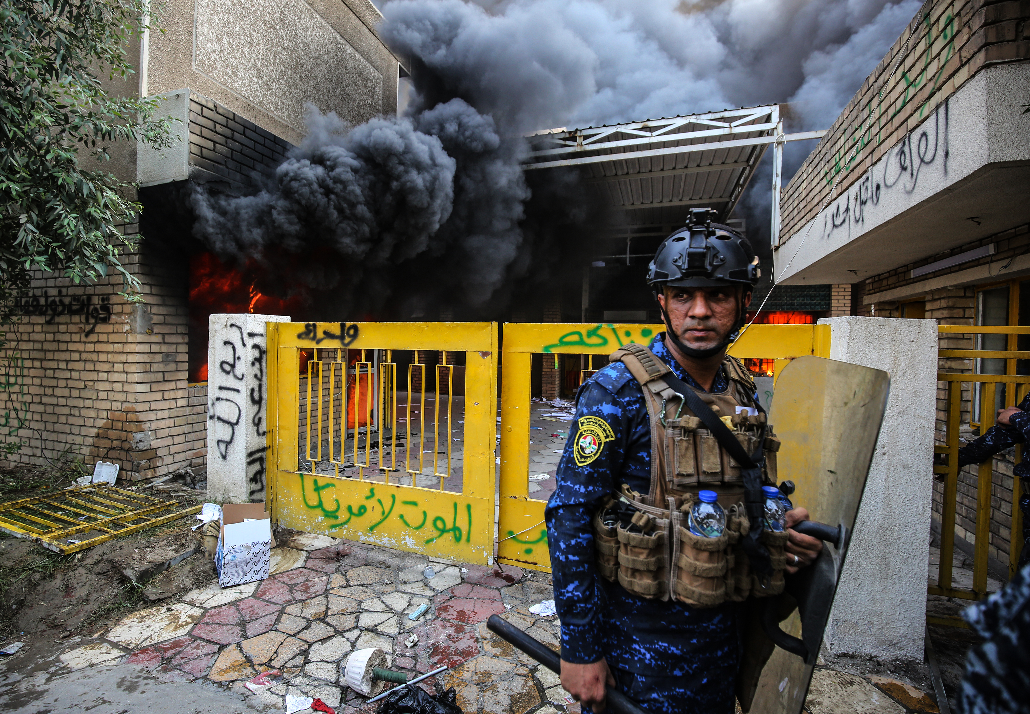 A member of the Iraqi security forces looks on as pro-Iranian militia supporters storm the main Baghdad office of the Kurdistan Democratic Party, Oct. 17, 2020. (Photo: AFP/Ahmad al-Rubaye)