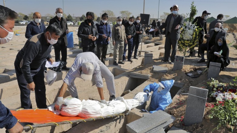 The body of a person who died from COVID-19 is interred as mourners look on at the Behesht-e-Zahra cemetery on the outskirts of Tehran, Iran, Sunday, Nov. 1, 2020. The cemetery is struggling to keep up with the coronavirus pandemic ravaging Iran, with double the usual number of bodies arriving each day and grave diggers excavating thousands of new plots. (Photo: AP/Ebrahim Noroozi)