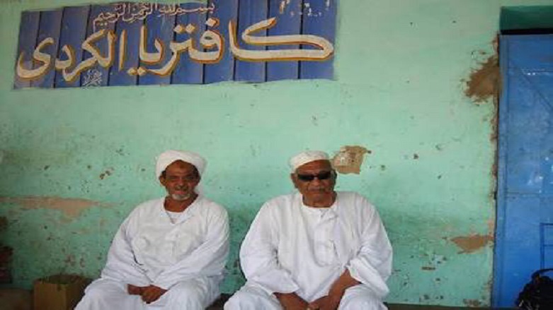 Sudan'da Kürt Cafeterya tabelası önünde oturan ve Kürt asıllı olduklarını söyleyen iki Sudanlı